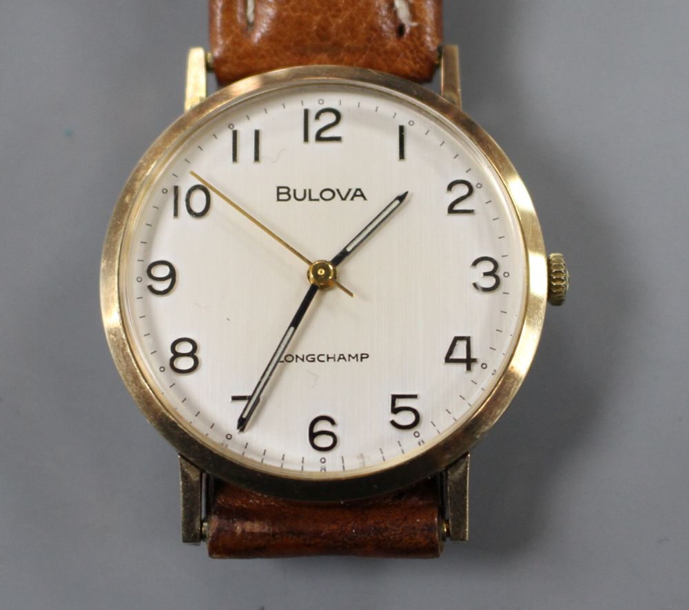 A gentlemans 9ct gold Bulova Longchamp manual wind wrist watch, on associated strap.